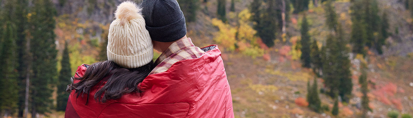 A man and a woman snuggle together in their TETON Sports Outdoor Camp Blanket