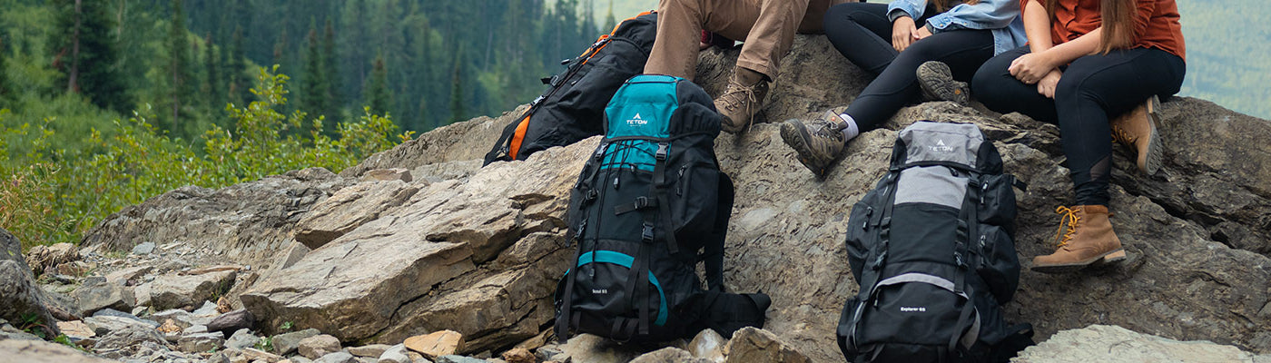 Three friends sit atop a rocky outcrop with their TETON Sports backpacks.