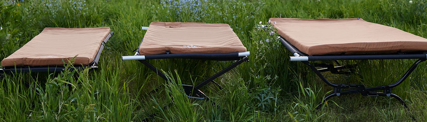 TETON Sports camp cots with canvas camp pads are set up showcasing three different sizes.