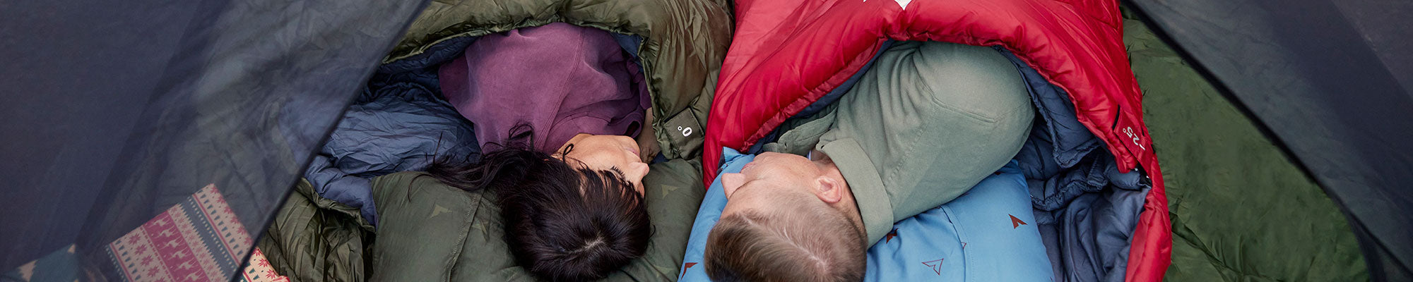A man and a woman lying in sleeping bags with their new TETON Sports Grand Pillows.