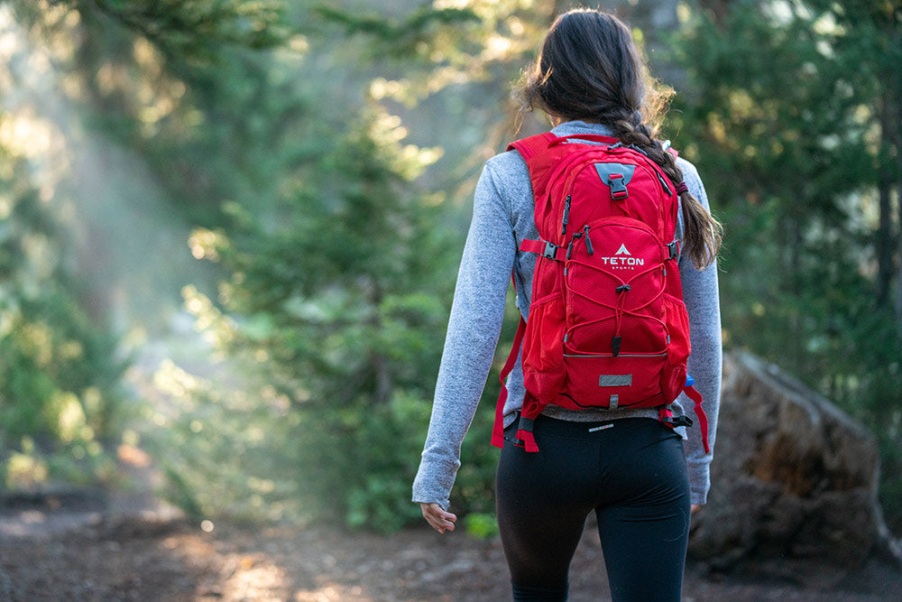 Woman walking with backpack through woods. 