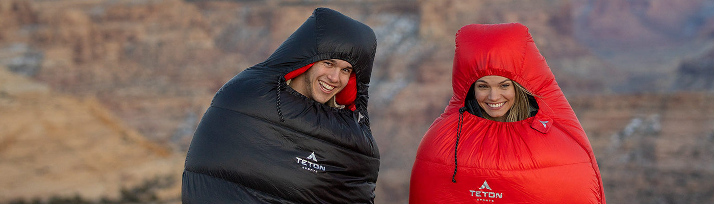 A couple poses together while wearing TETON Sports ALTOS Mummy Sleeping Bags.