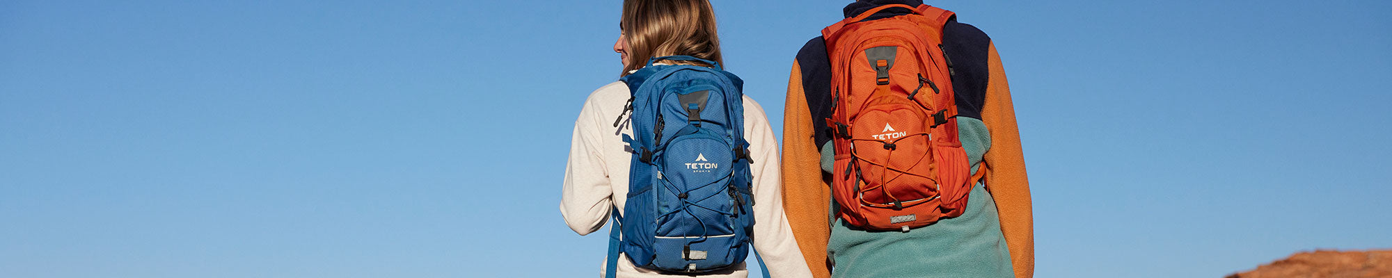 A woman sips from her TETON Sports Oasis Backpack while hiking inside a forest.