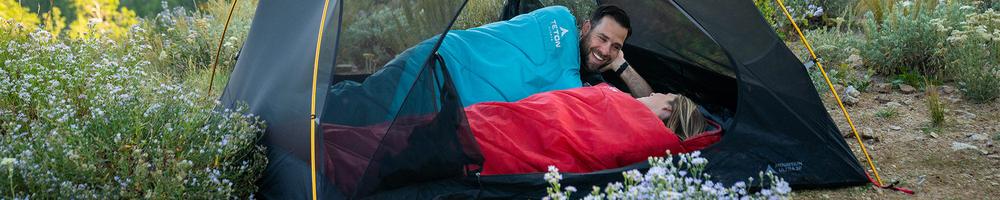 A couple talk together from inside their Mountain Ultra Tent while inside their new Celsius Sleeping Bags.