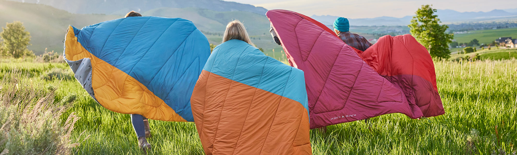 Friends running through a field with their TETON Sports Acadia and Highline outdoor camp blankets.