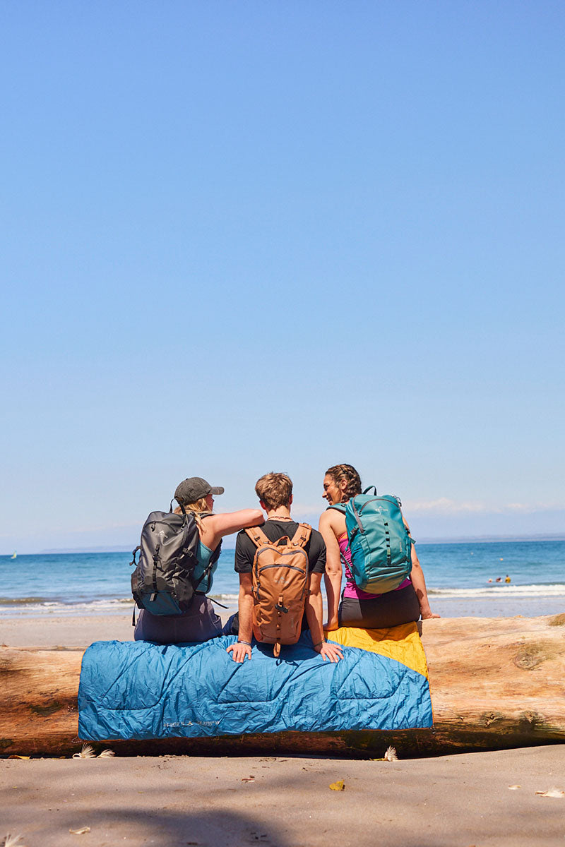 A group of friends at the beach with their Numa daypacks and Highline blanket.