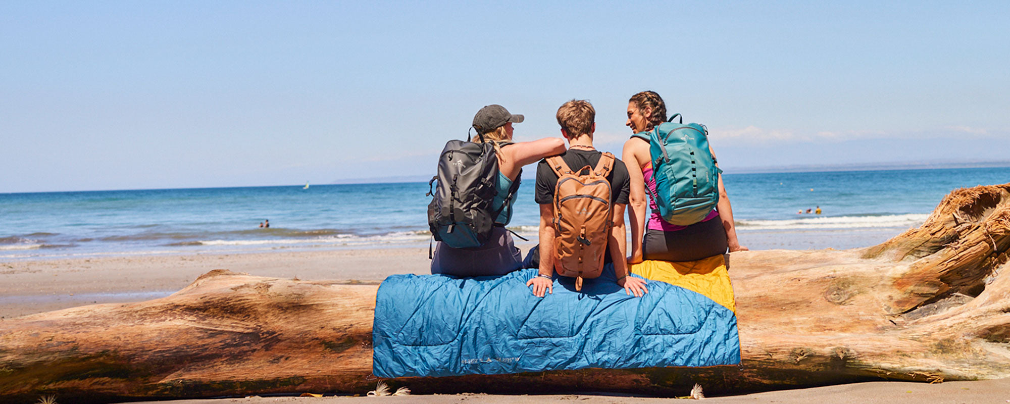 A group of friends at the beach with their Highline blanket and Numa daypacks.