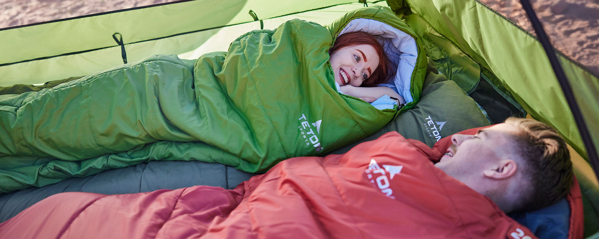 A man and woman in their leef sleeping bags.