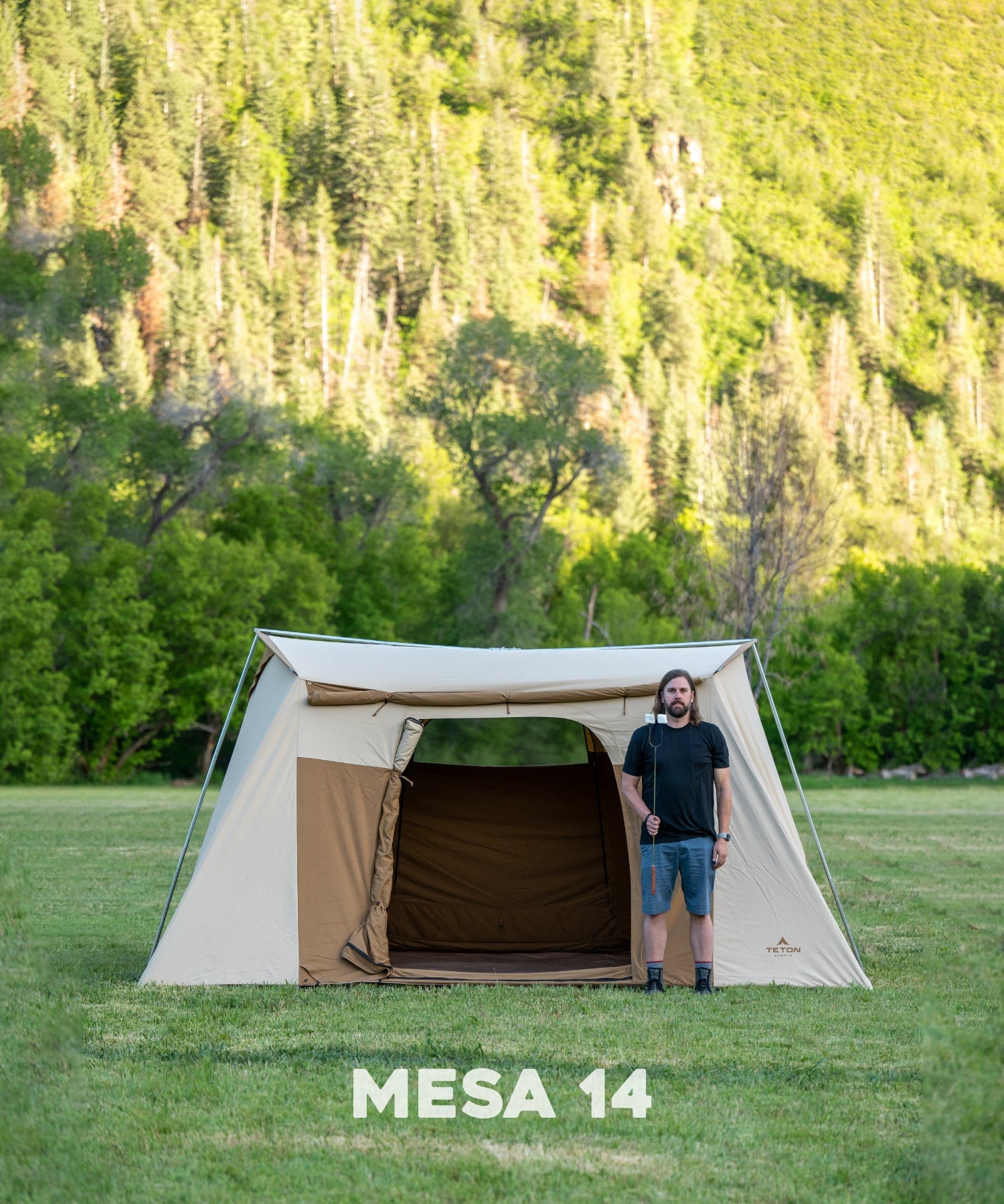 The TETON Sports Mesa 10' x 14' Canvas Tent: : Image shows a man standing in front of the tent with a marshmallow stick to show comparative size.